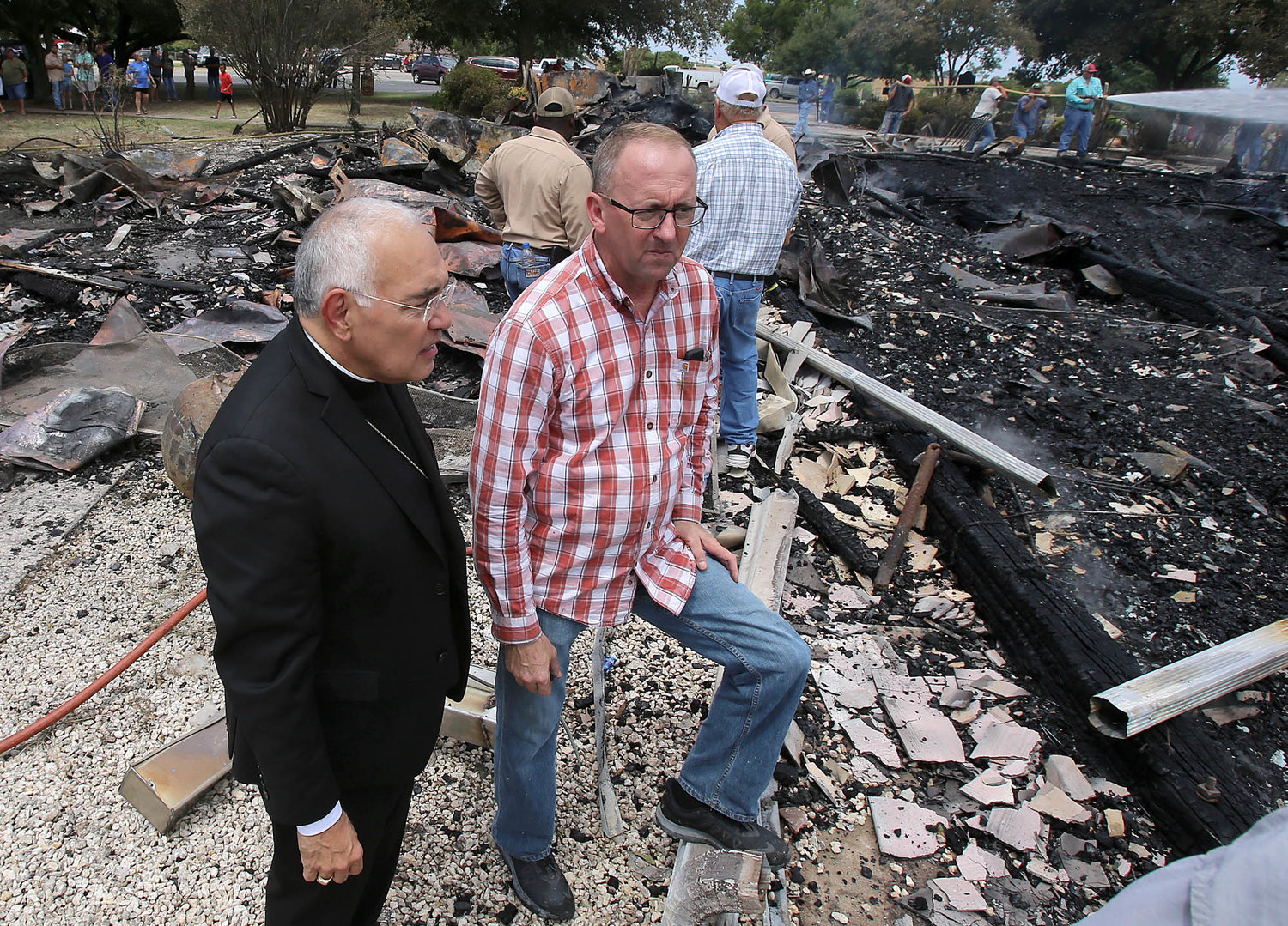 Bishop Joe S. Vasquez of Austin, Texas, and Father Darrell Kostiha, pastor at St. Joseph Parish in Cyclone and Sts. Cyril and Methodius Mission in Marak, look through debris of the Church of the Visitation in Westphalia July 29, 2019, after the 124-year-old church was destroyed in a fire. Since 1883 the parish has served the Catholic community of southwestern Falls County, many of whom are descendents of immigrants from the northwest German region of Westphalia.